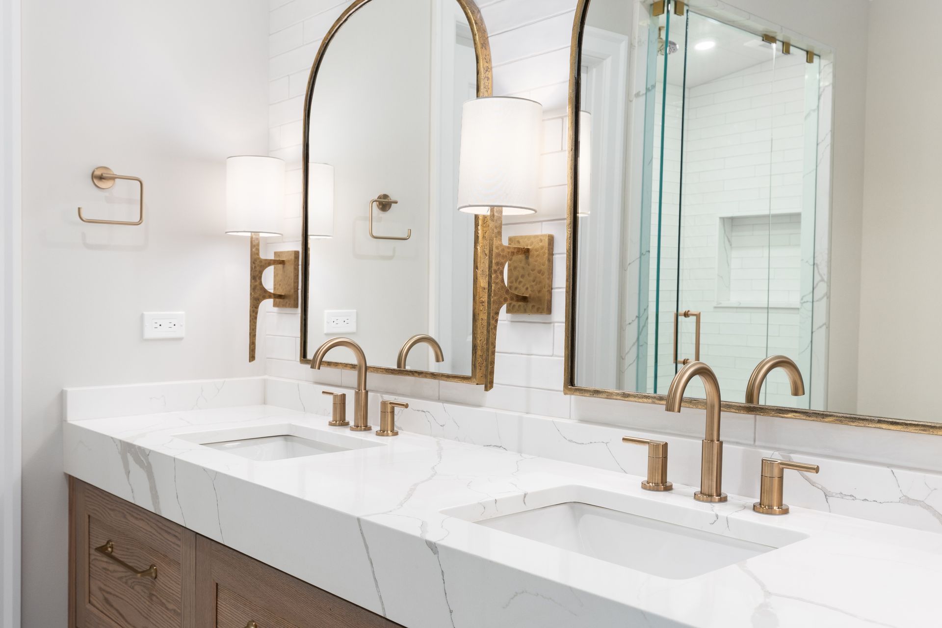 Bright double vanity bathroom with gold mirrors, faucets, and white countertops
