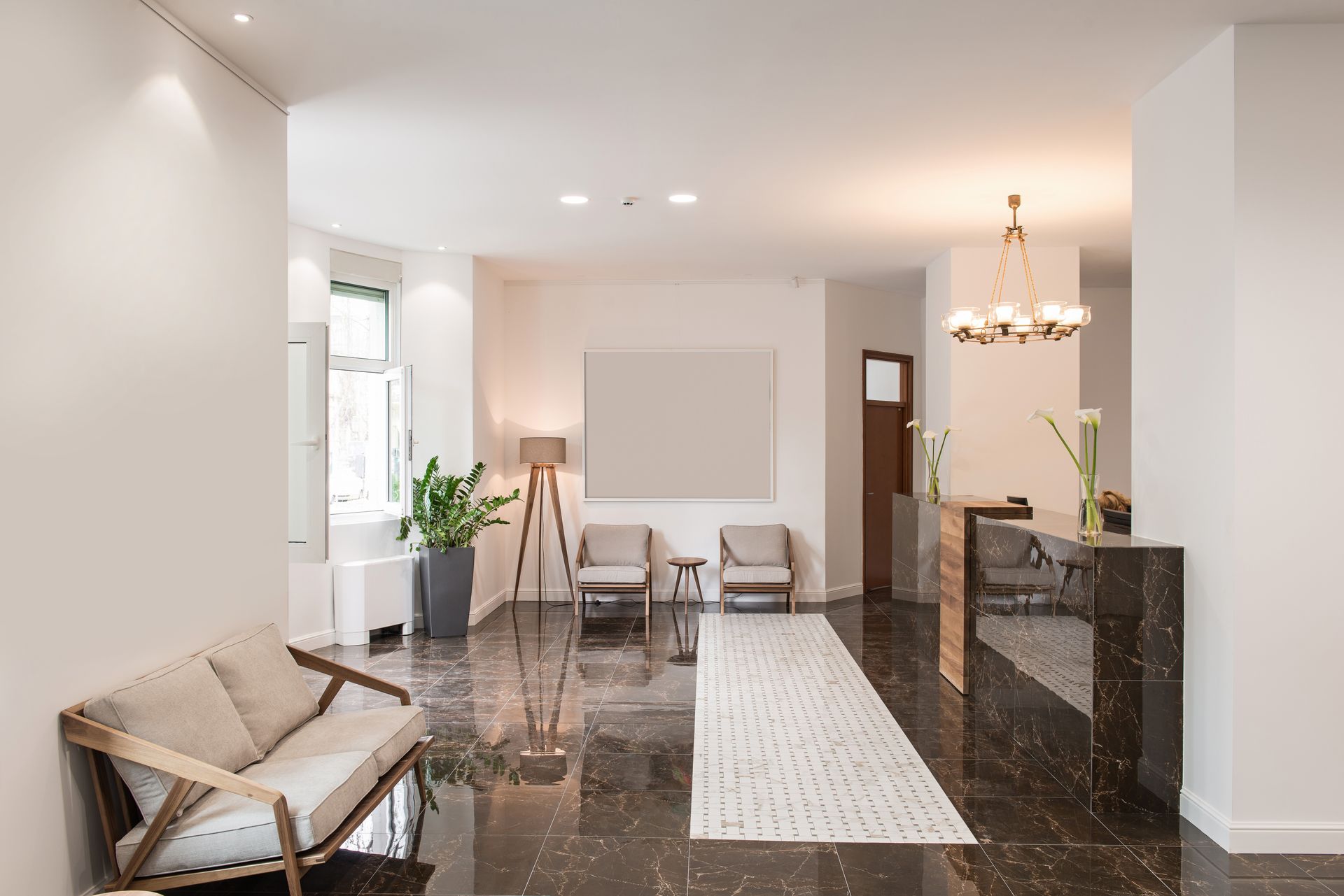 Modern living room with white walls, dark floor, chairs, sofa, lamp, and a long rug.