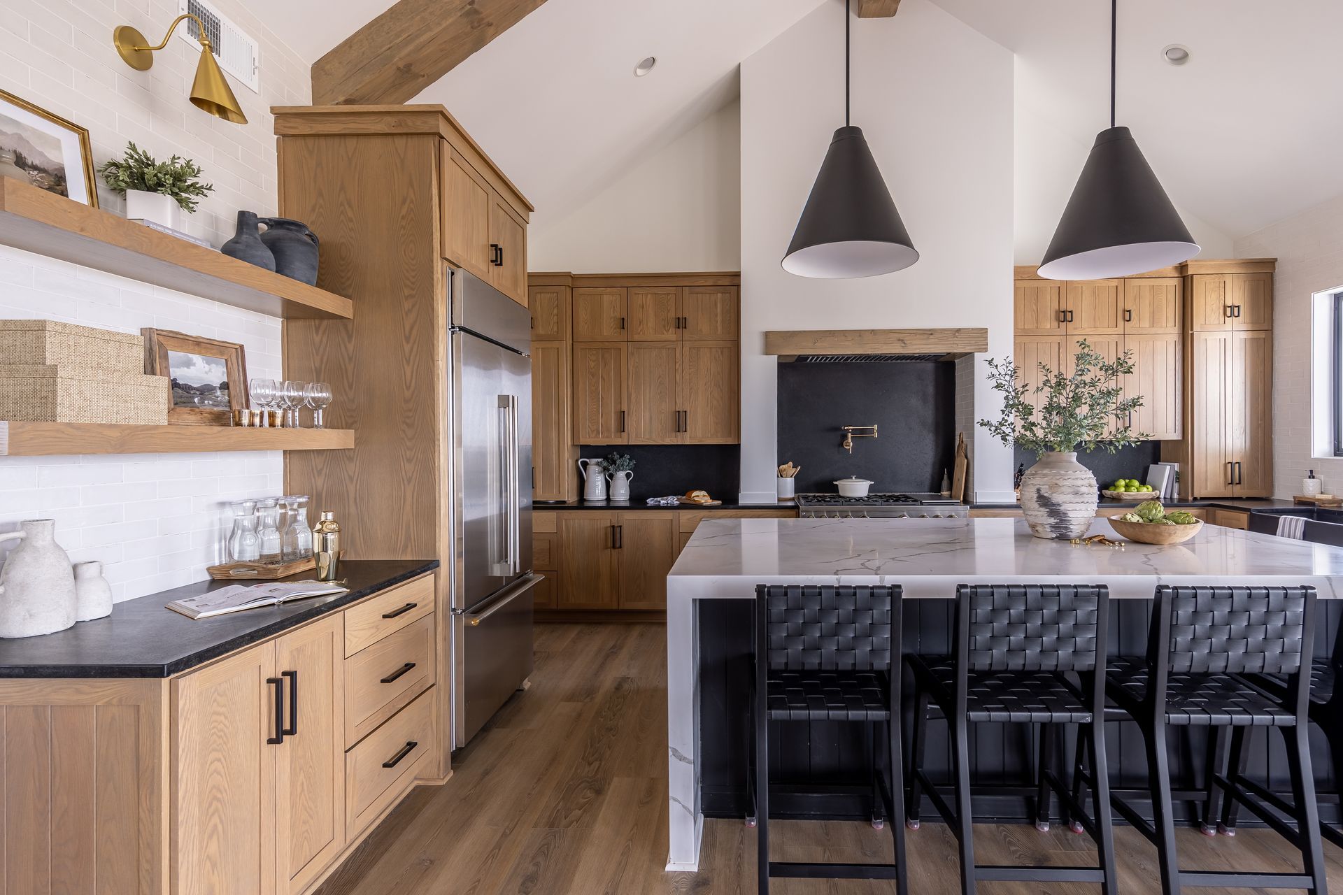 Modern kitchen with island, black pendant lights, wood cabinets, and stainless steel appliances