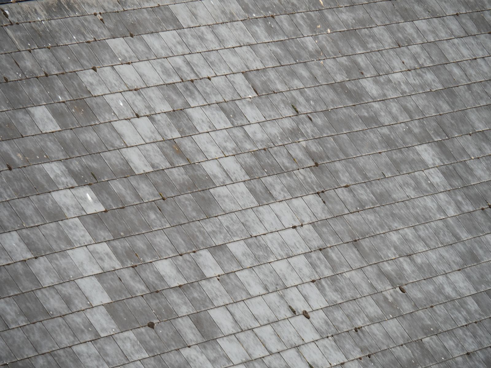 Close-up view of a weathered, gray shingled roof with a diamond-patterned arrangement.