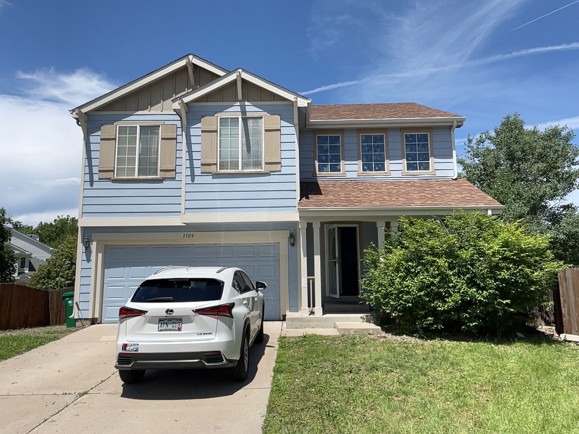 Gray garage door on a house with stone accents. Door has windows and decorative hardware, address 