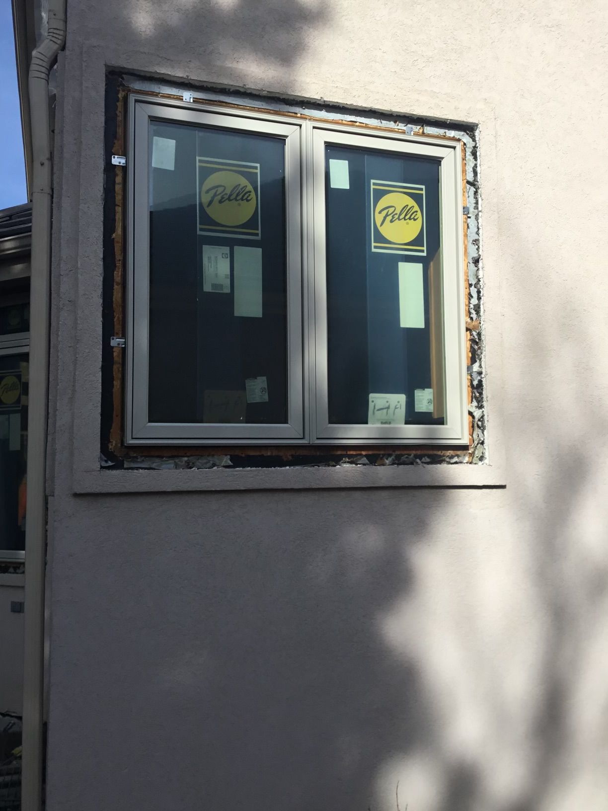 Window replacement in progress; new white-framed window installed in a stucco wall. The window is covered in protective film.
