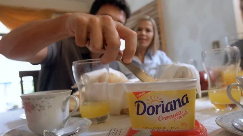 Um homem está espalhando manteiga doriana sobre uma mesa