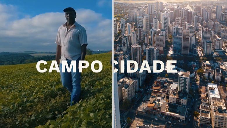 Um homem está parado no topo de uma colina gramada próximo a uma cidade.