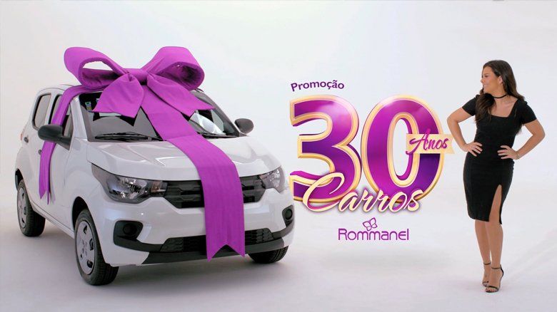 Uma mulher de vestido preto está parada ao lado de um carro branco com um laço roxo.