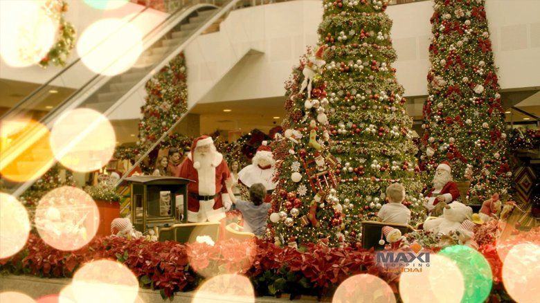 Um grupo de papais noéis está em frente a uma árvore de natal em um shopping.
