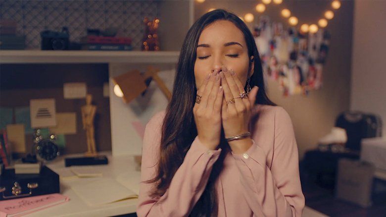 Uma mulher está sentada em uma mesa cobrindo a boca com as mãos.