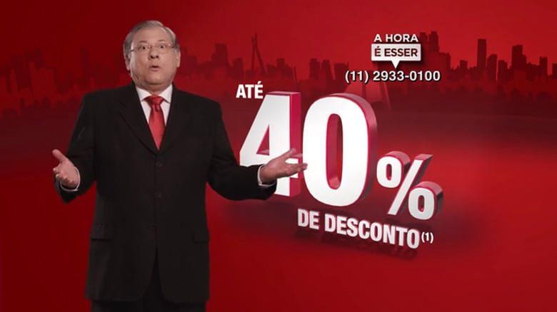 Um homem de terno e gravata está em frente a uma placa que diz 40% de desconto