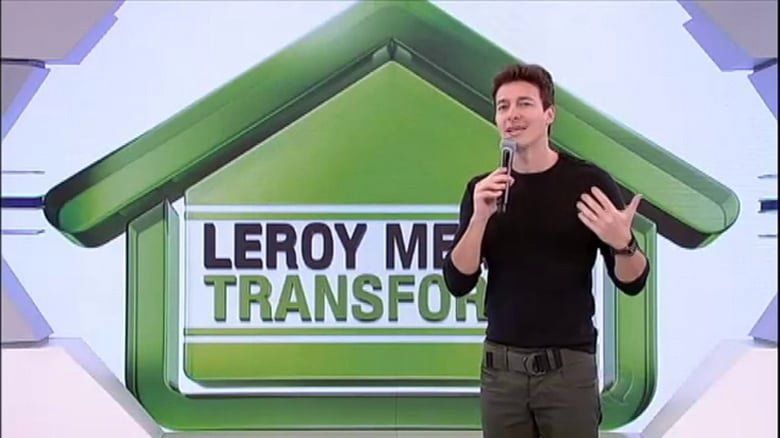 Um homem está parado em frente a um logotipo de leroy merlin