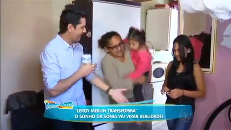 Um grupo de pessoas está em uma sala e uma delas está segurando uma criança