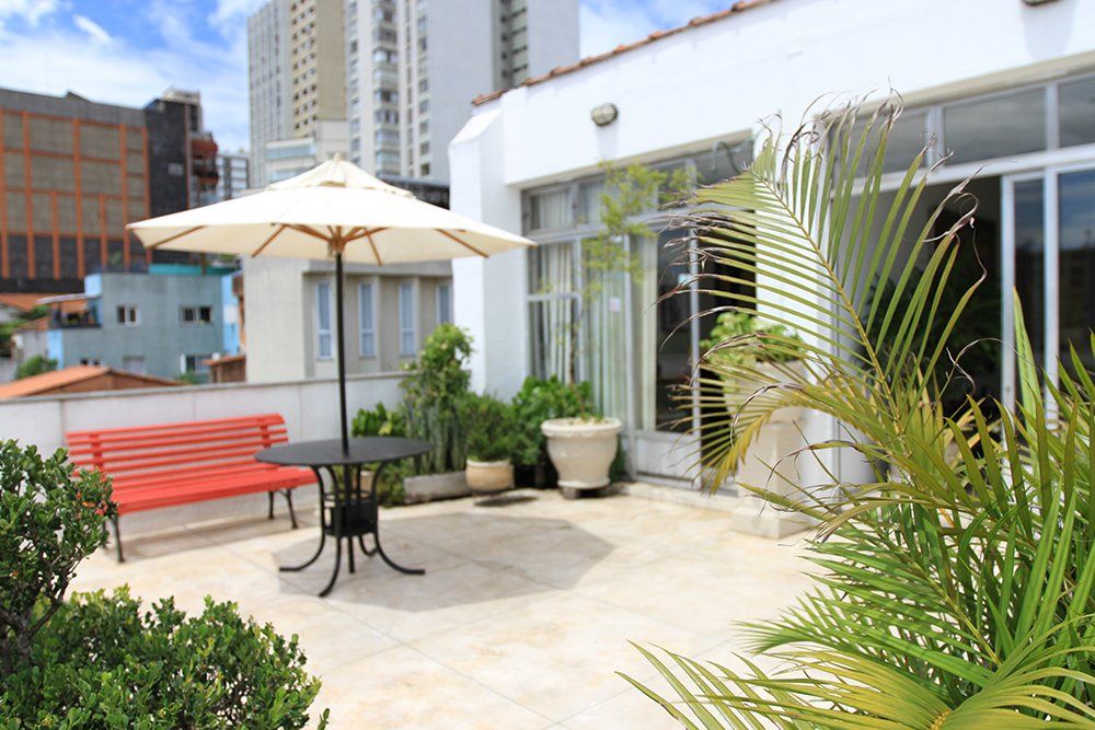 Um pátio com mesa e guarda-chuva e um banco vermelho