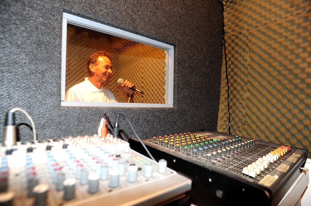 Um homem está cantando em um microfone em um estúdio de gravação