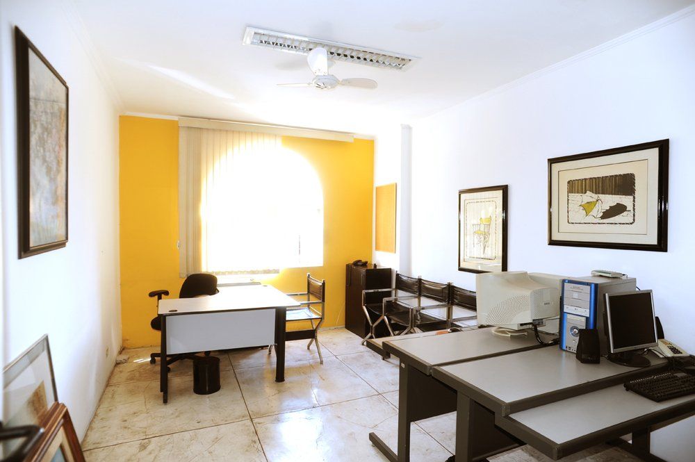 Um escritório com paredes amarelas e mesas e cadeiras brancas