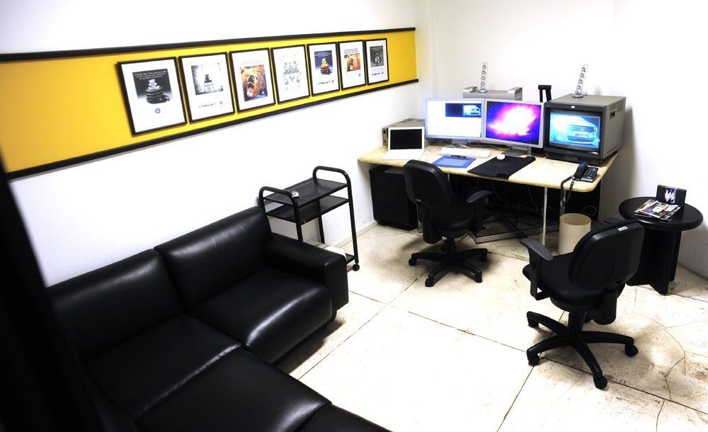 Uma sala com um sofá, uma mesa e dois computadores