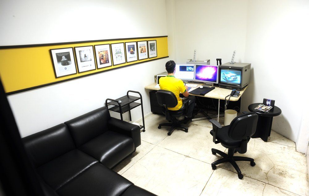 Um homem de camisa amarela está sentado em uma mesa em uma sala