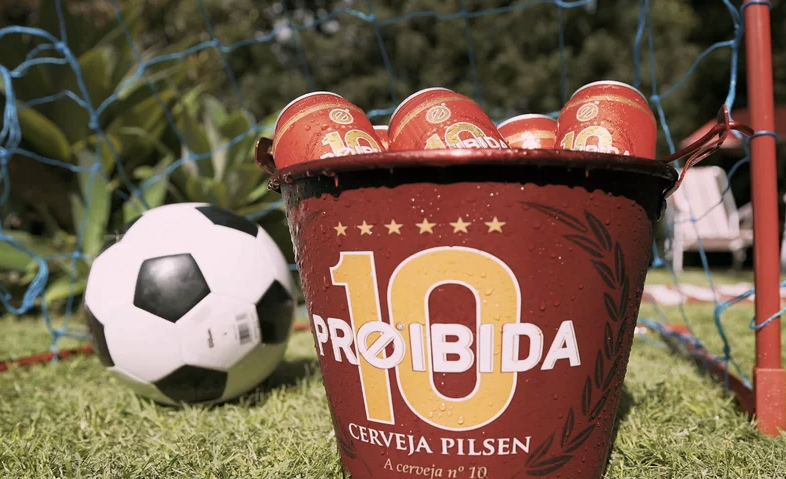 Um balde de cerveja está na grama ao lado de uma bola de futebol.