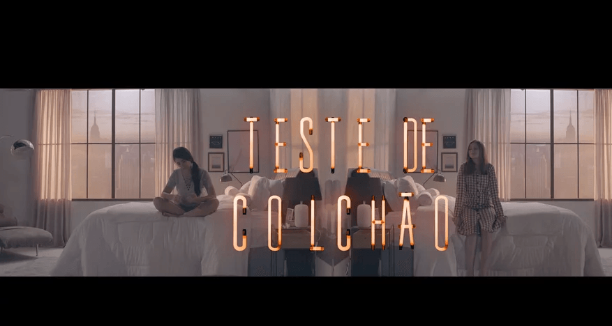 Um grupo de mulheres está sentado em cima de uma cama em um quarto.