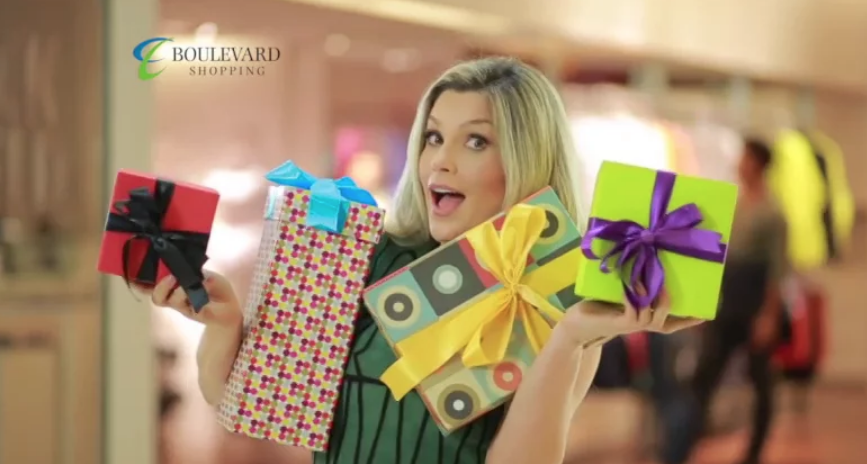 Uma mulher está segurando um monte de presentes nas mãos.