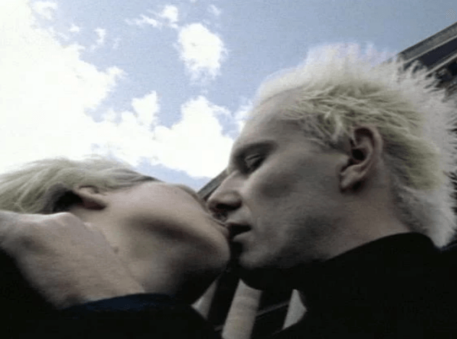 Um homem e uma mulher se beijando com um céu azul ao fundo