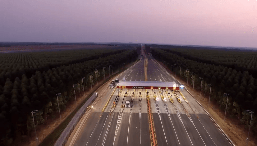 Uma vista aérea de um pedágio em uma rodovia cercada por árvores.