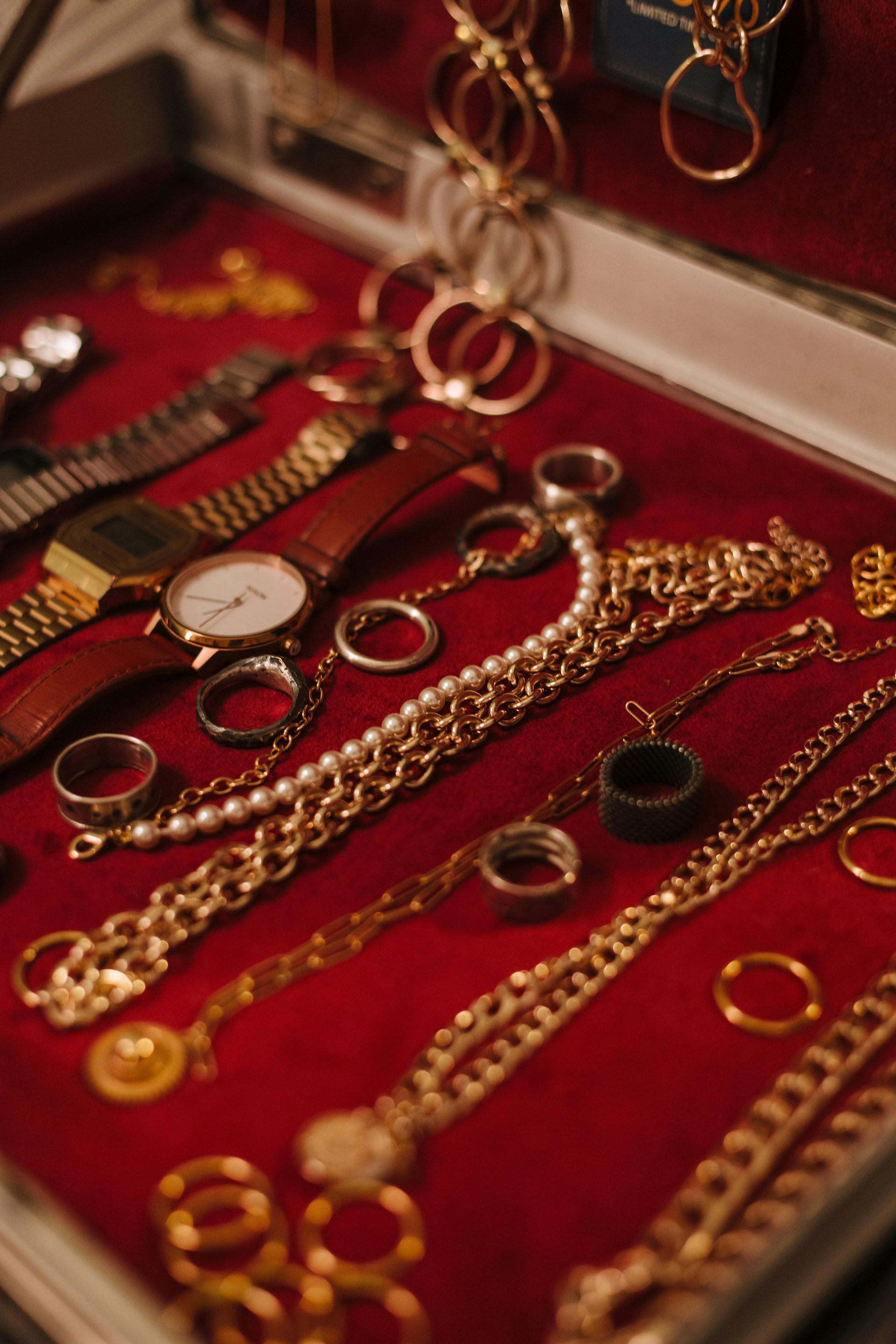 Gold jewelry and rings displayed on a red velvet tray in a display case