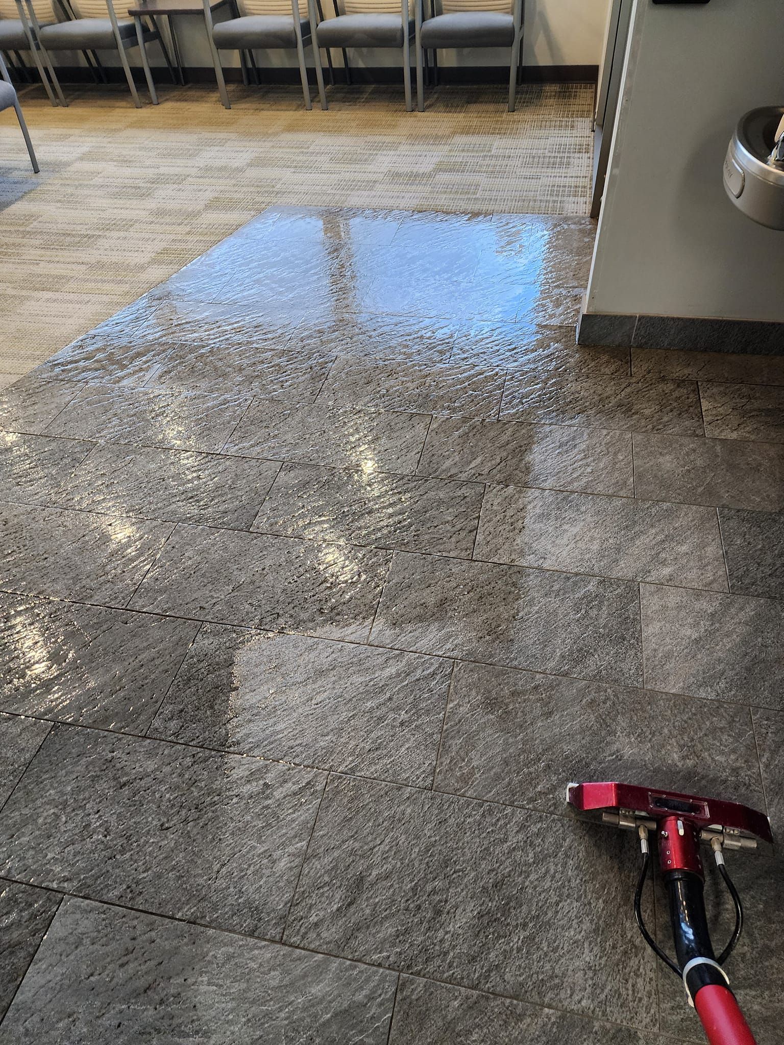 Strongarm Cleaners - A person is cleaning the floor of a room with a vacuum cleaner.
