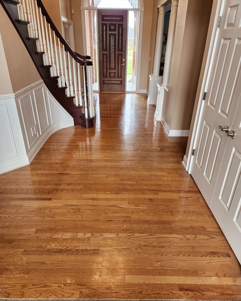 Strongarm Cleaners - A hallway with hardwood floors and stairs in a house.