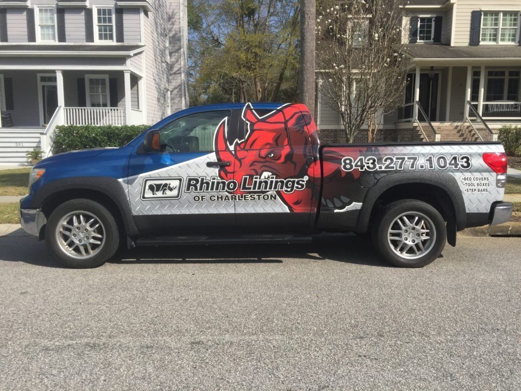 A rhino lifting truck is parked in front of a house.