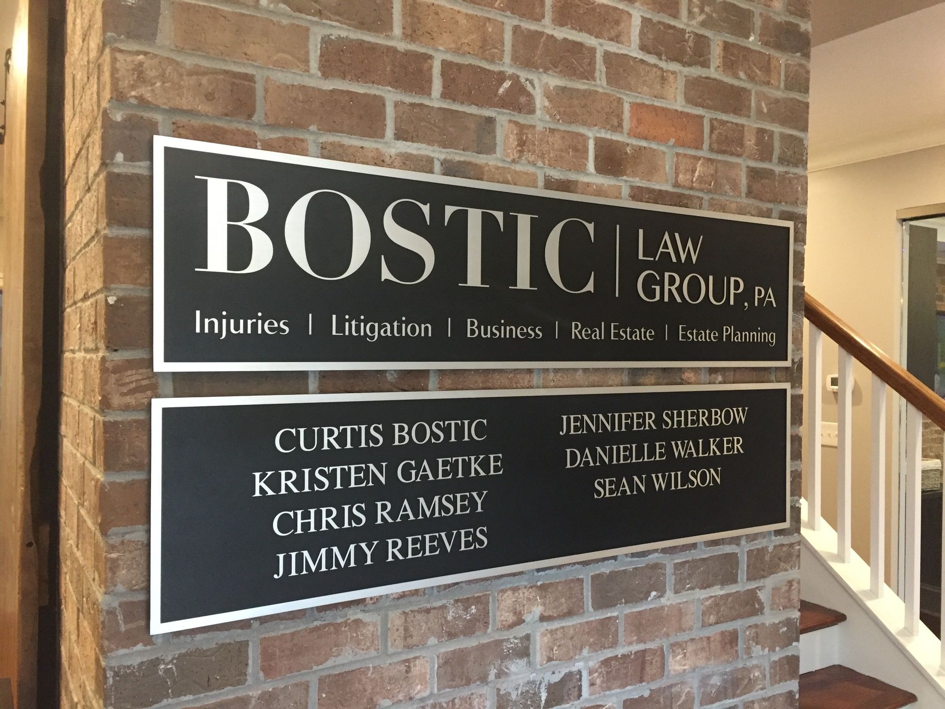 A sign for bostic law group is on a brick wall