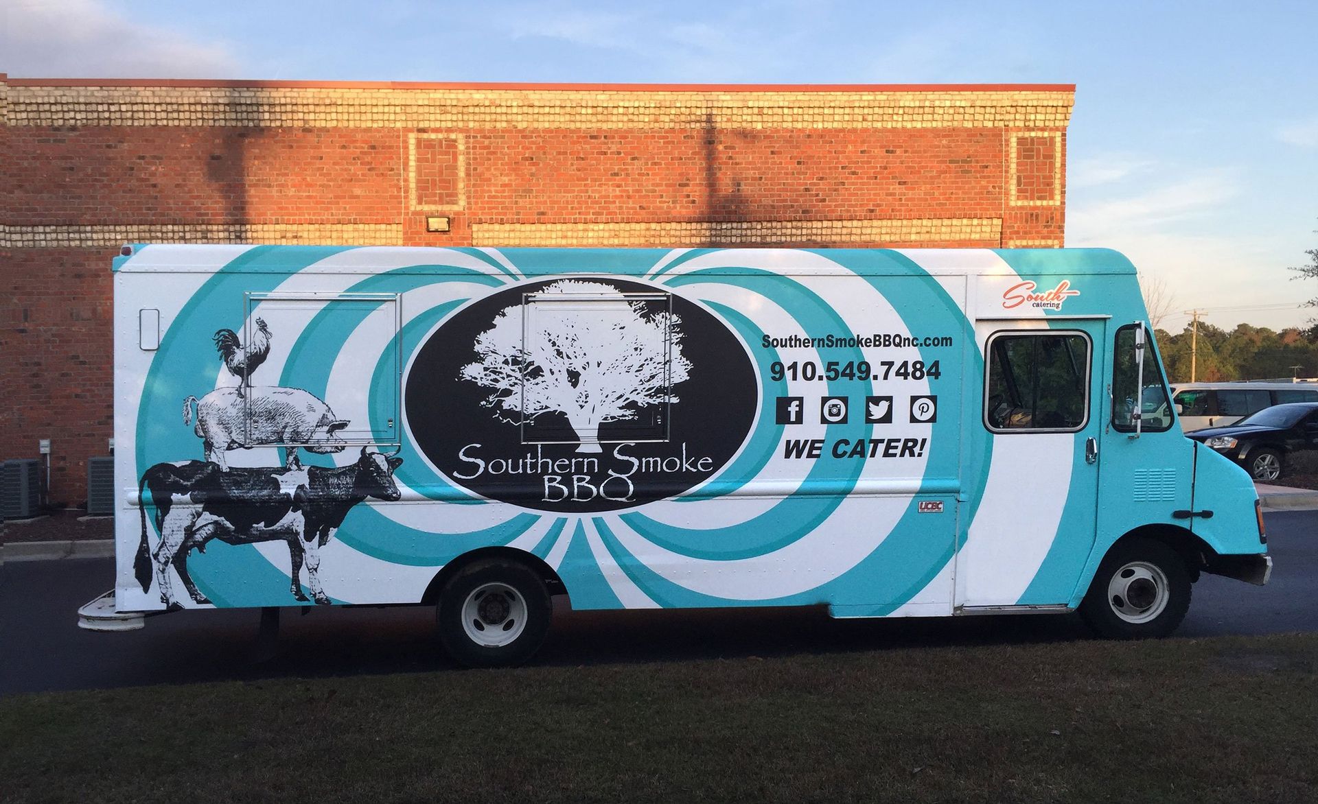 A blue and white food truck is parked in front of a brick building