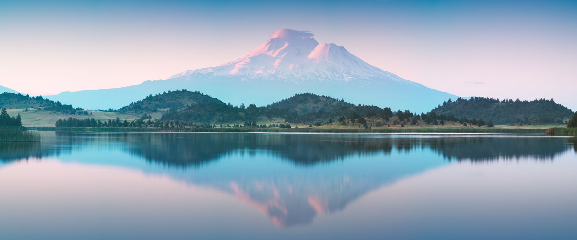 Gray house with wooden steps, picnic table, and blue sky.