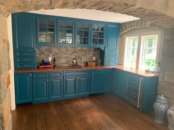 A kitchen with blue cabinets and wooden floors.
