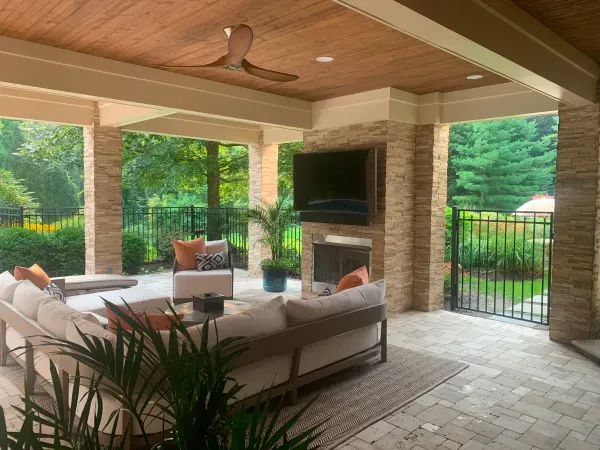 A living room with a couch , chairs , a fireplace and a ceiling fan.
