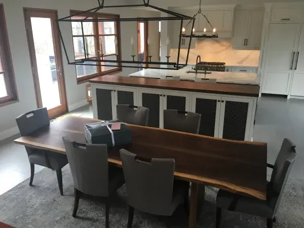 A dining room with a large wooden table and chairs