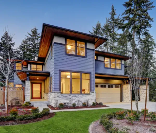 A blue house with a lot of windows is surrounded by trees.