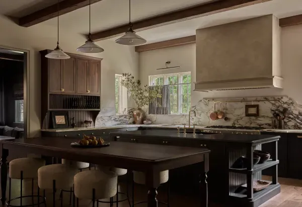 A kitchen with a large table and stools in it.