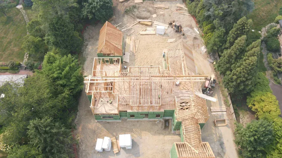 An aerial view of a house under construction in the middle of a forest.