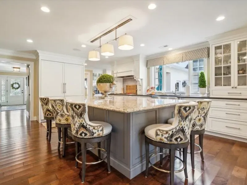 A kitchen with a large island and stools in it.
