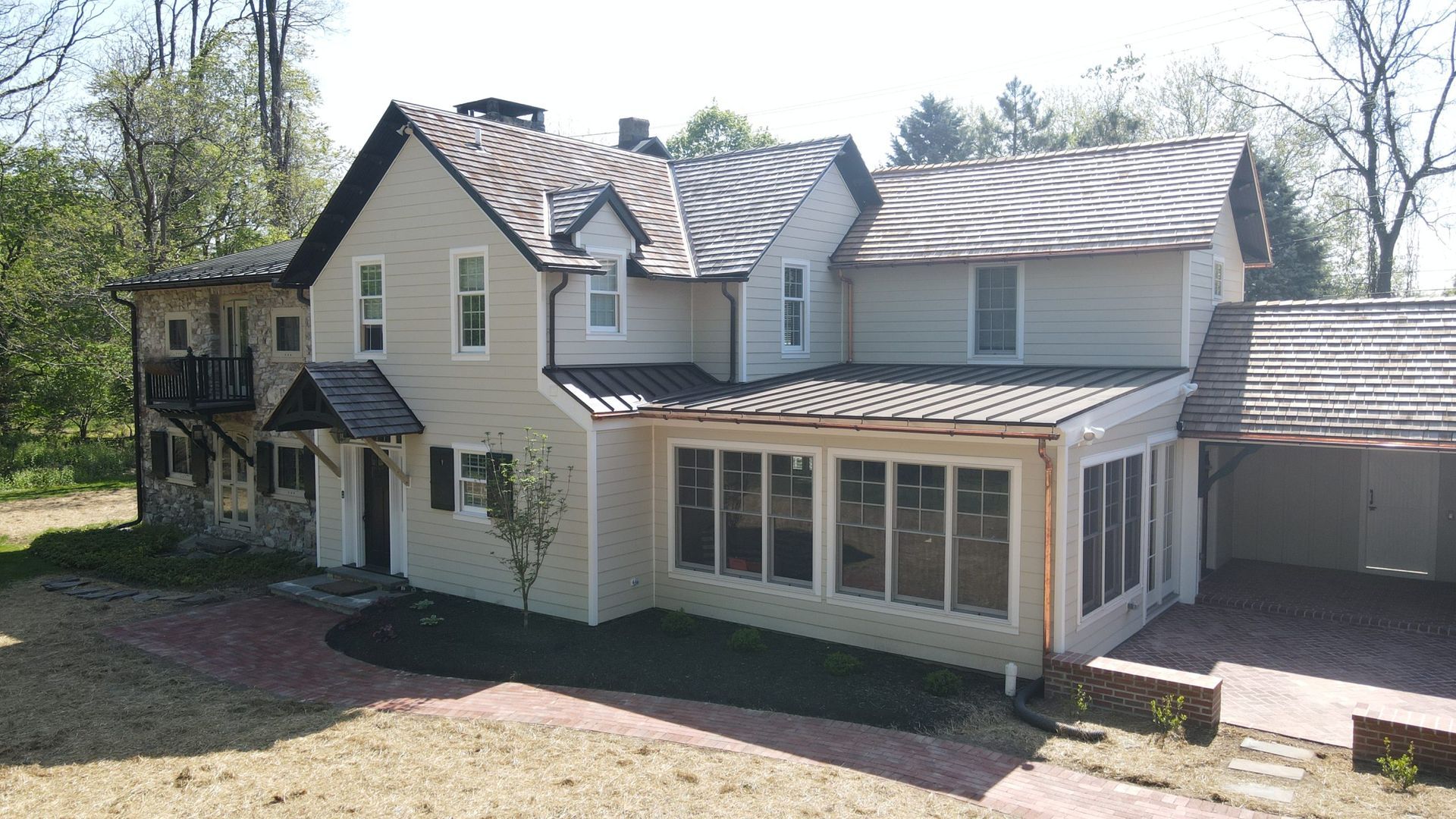 A large white house with a metal roof is surrounded by trees.