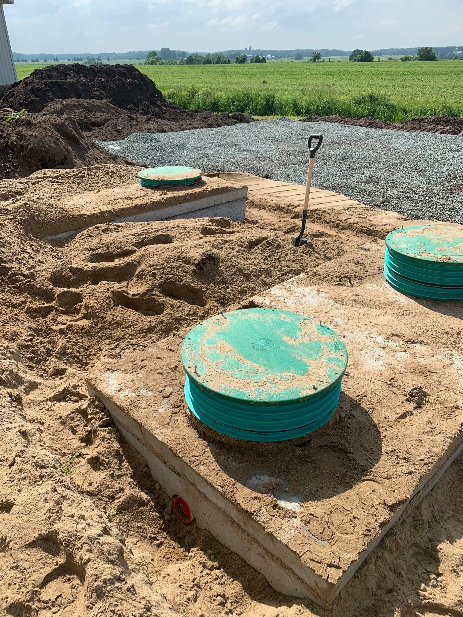 Une fosse septique est en cours de construction dans la terre à côté d'un champ.