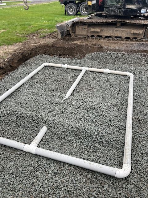 Un tuyau blanc est posé sur un tas de gravier.