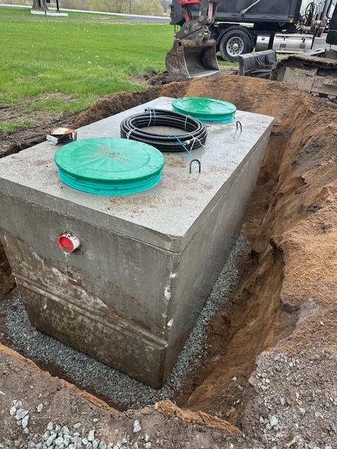 Une fosse septique en béton est en cours d'installation dans un trou dans le sol.