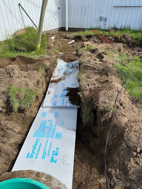 Un tuyau de drainage est en train d'être installé dans un trou dans le sol.