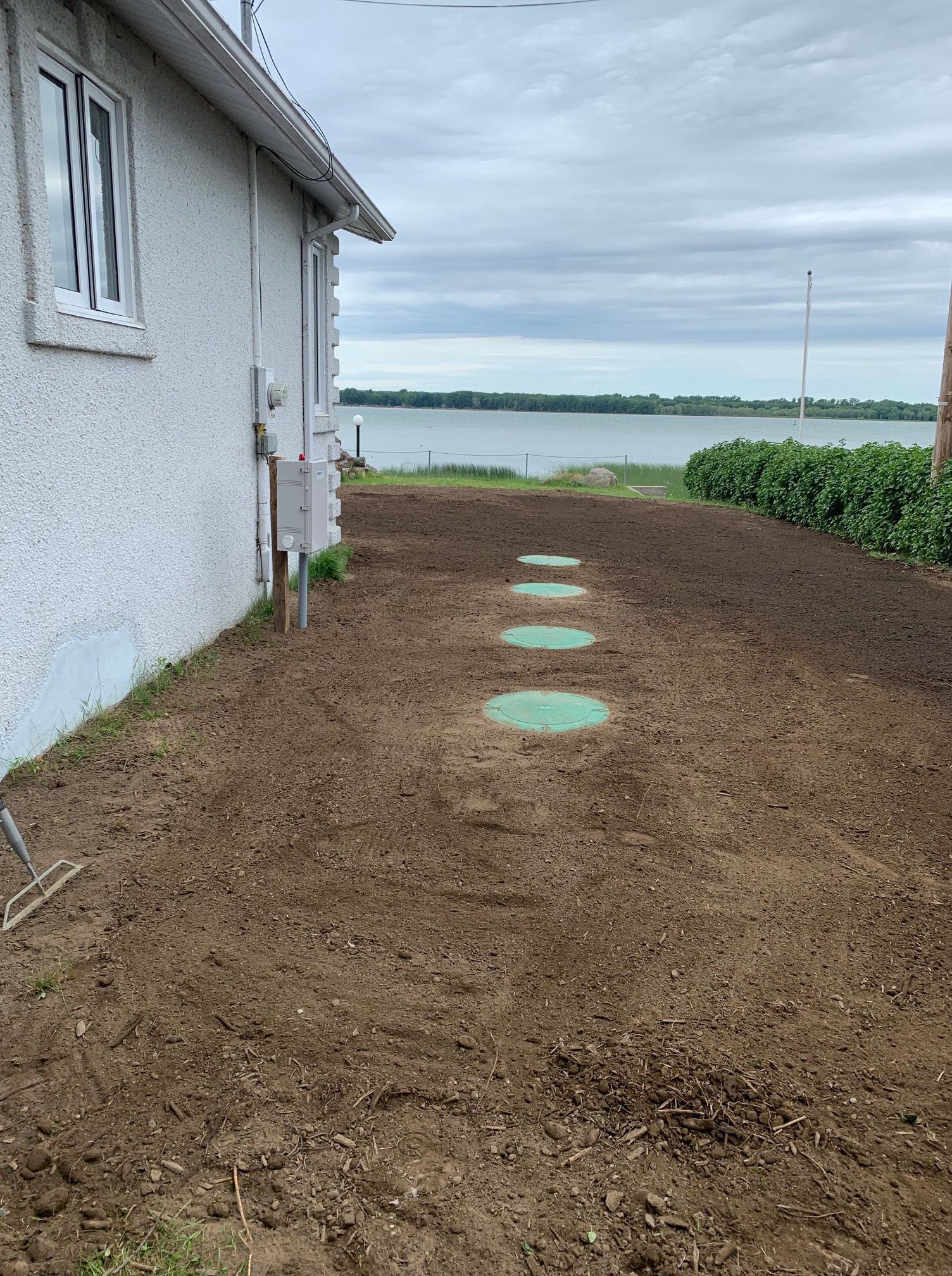 Une maison avec beaucoup de terre devant et un lac en arrière-plan.