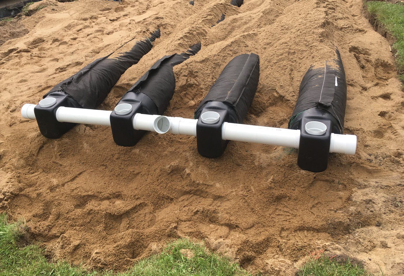 Une rangée de tuyaux posée sur un tas de sable.