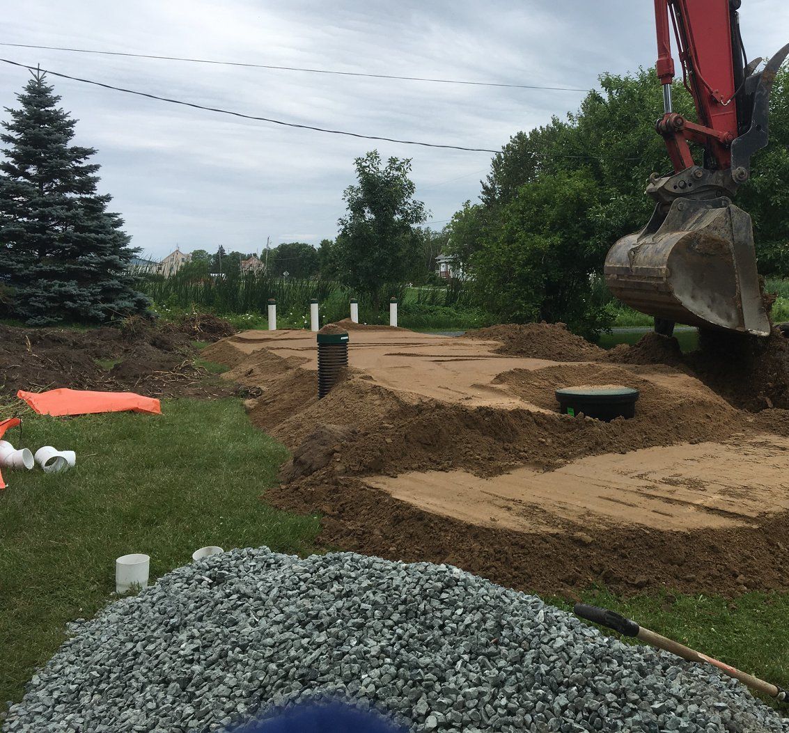 Une excavatrice rouge creuse un trou dans le sol.