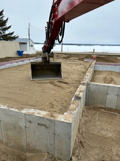 Une grue rouge soulève un grand seau de terre