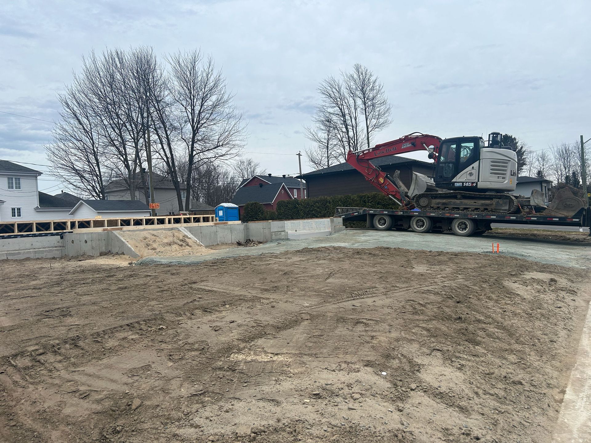 Une grande excavatrice est assise sur une remorque dans un champ de terre.