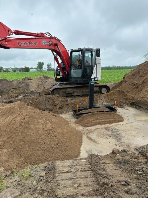 Une excavatrice rouge creuse un trou dans la terre