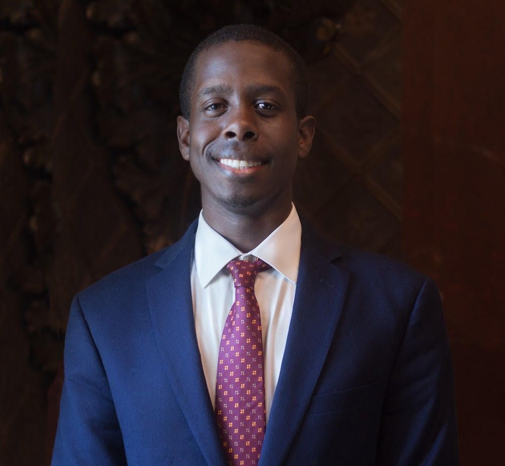 A man in a suit and tie is smiling for the camera